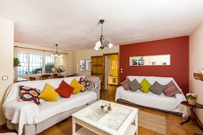 A living room with two sofas, a coffee table, and a dining area with chairs and a table.