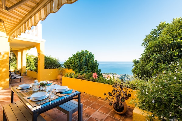 An outdoor dining area with a table set for four, overlooking a scenic view of the ocean.