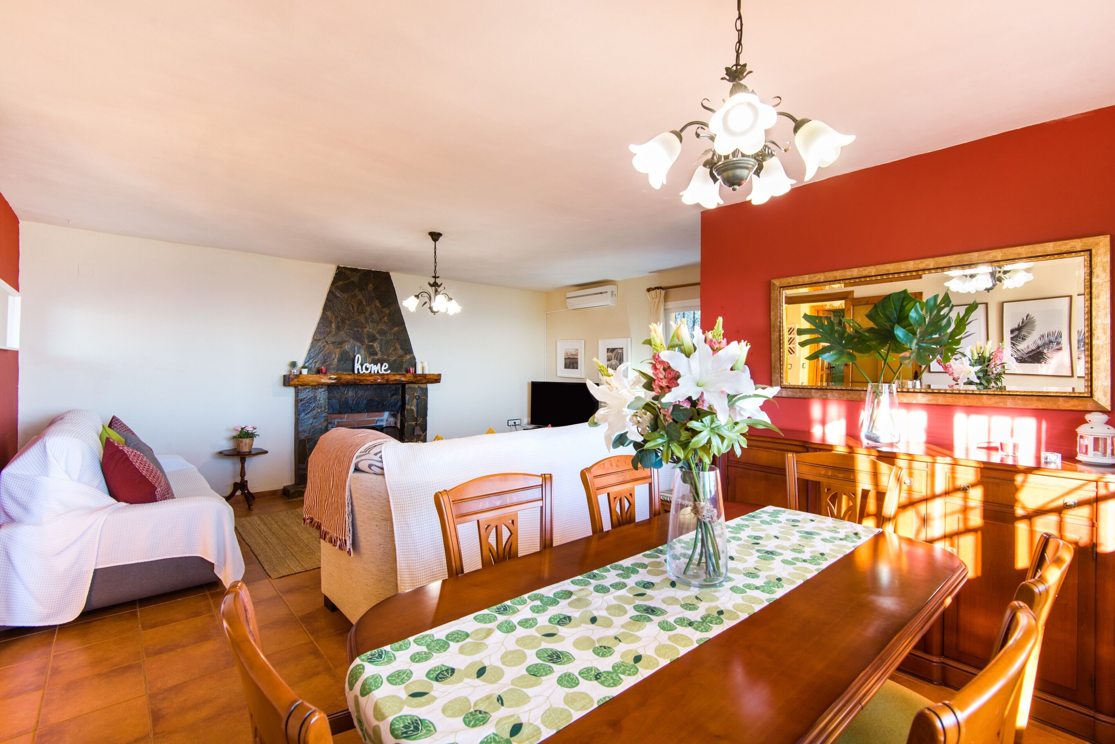 A cozy room with a bed, a dining table with chairs, a fireplace, and a mirror on the wall.