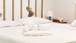 Un letto rifatto con asciugamani arrotolati e una lampada sul comodino.