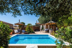 A swimming pool with lounge chairs and umbrellas, surrounded by greenery. - Vacation Home "Casa Martin" with Mountain View, Private Pool & Wi-Fi (Calvià)