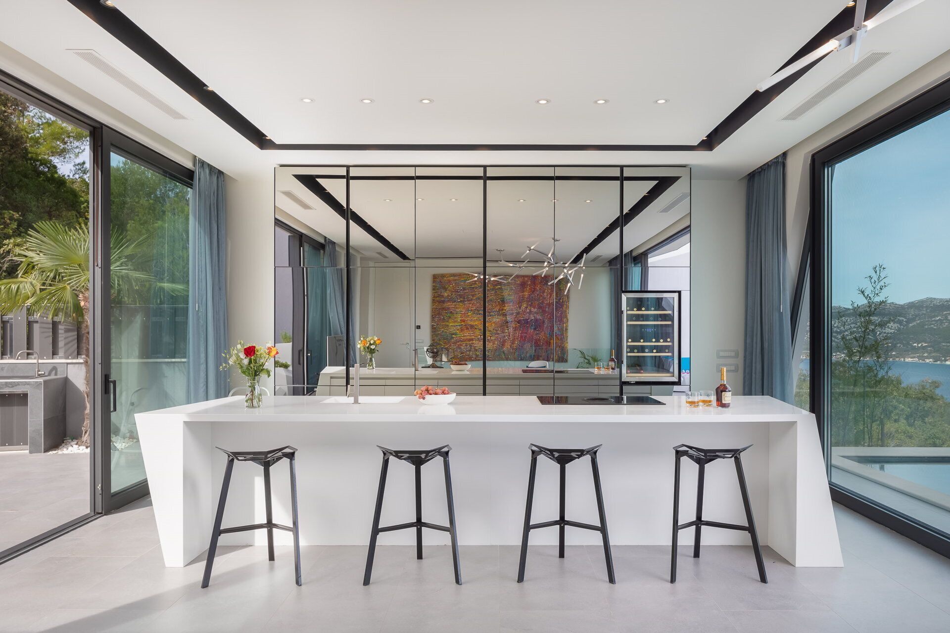 A modern kitchen with a large island, bar stools, and a view of the outdoors.