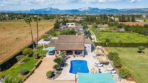 Una casa con piscina, rodeada de césped cuidado y vistas a las montañas.