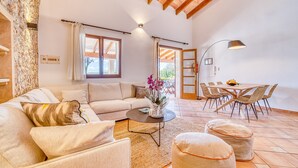 Una sala de estar con sofá, mesa de centro, reposapiés, mesa de comedor con sillas y una lámpara.
