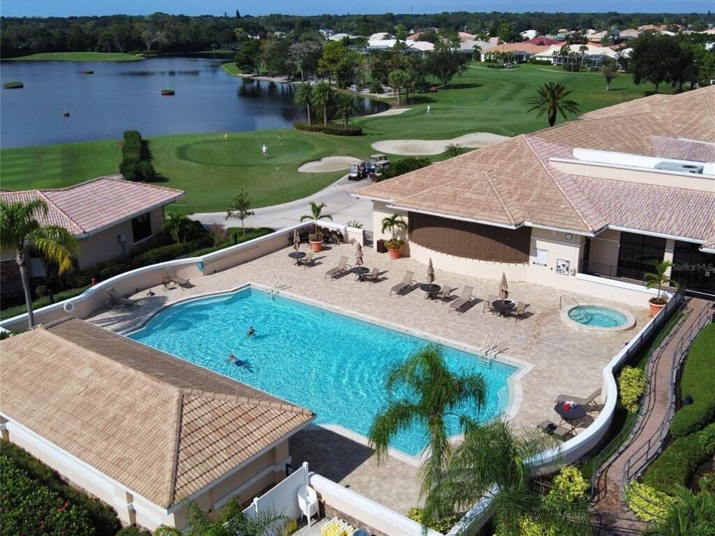 A resort with a swimming pool, lounge chairs, and a golf course in the background.