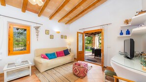Una sala de estar con sofá, reposapiés, televisor y una mesa de vidrio.