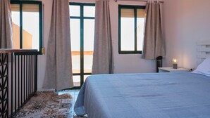 Une chambre à coucher avec un lit, une table de chevet, une lampe et une fenêtre avec des rideaux.