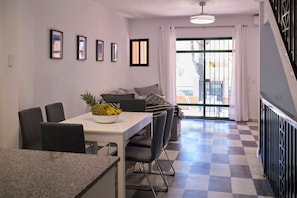 A dining area with a table, chairs, and a fruit bowl. There is a staircase with a railing on the right. - Holiday Home "Marisa" with Pool, Garden, Terrace, Balcony & Wi-Fi (Chiclana de la frontera)
