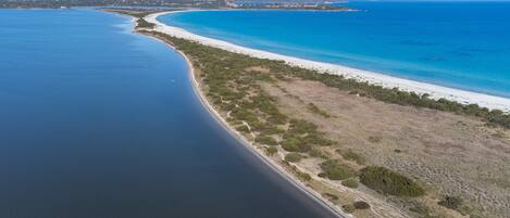Eine Luftaufnahme einer Küstenlandschaft mit Strand, klarem, blauem Wasser und einem Berg im Hintergrund.