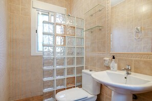 A bathroom with a toilet, sink, and a glass block window.