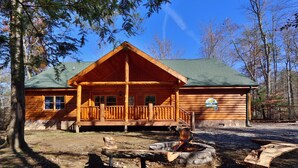 A log cabin with a porch, a fire pit, and a sign indicating '224 AMET WAY'. - Splash N' Play #524 (Cosby)