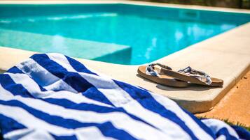 Ein Poolbereich mit einem blau-weiß gestreiften Handtuch und einem Paar Sandalen.