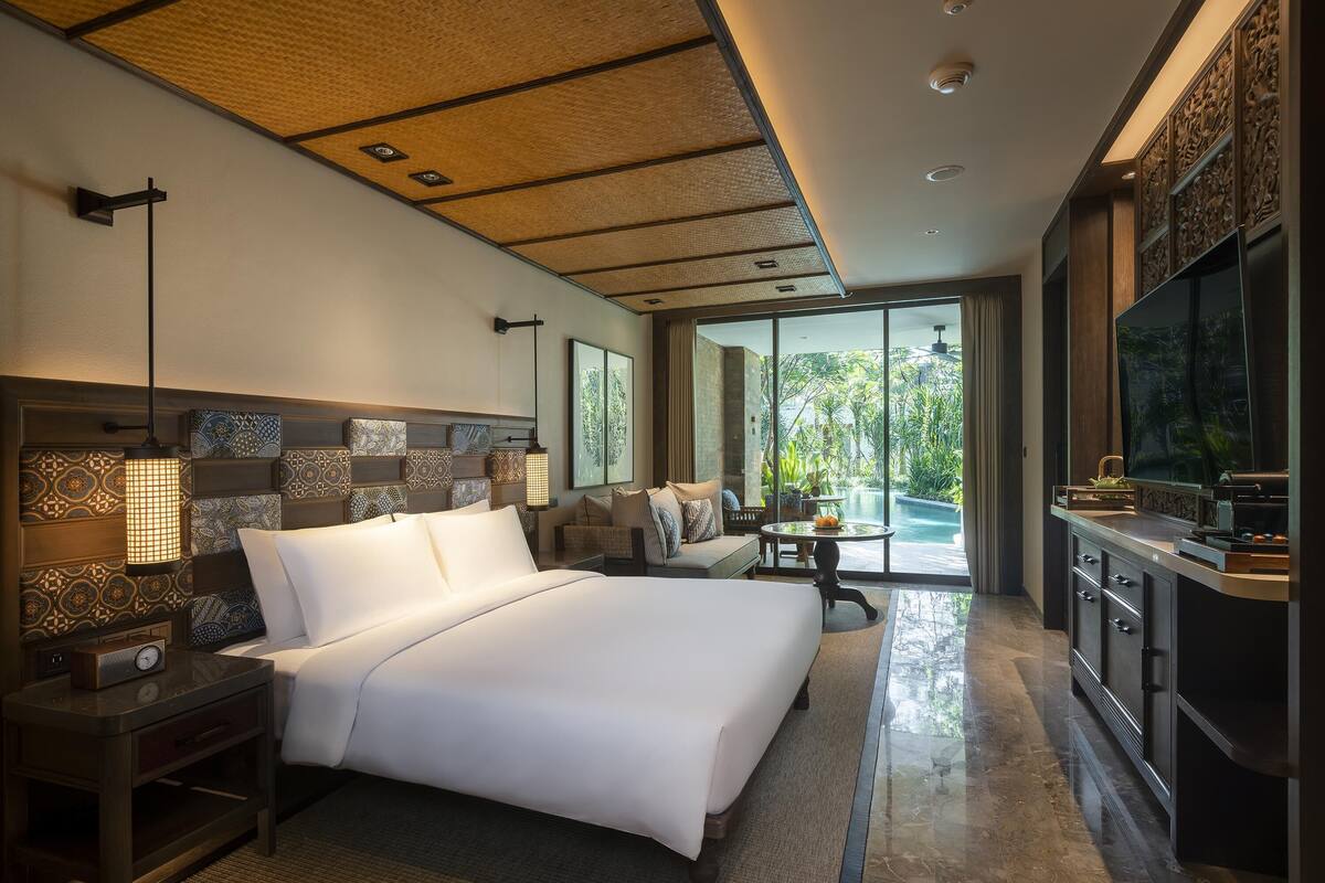 A spacious bedroom with a large bed, a TV, and a view of the outdoors.