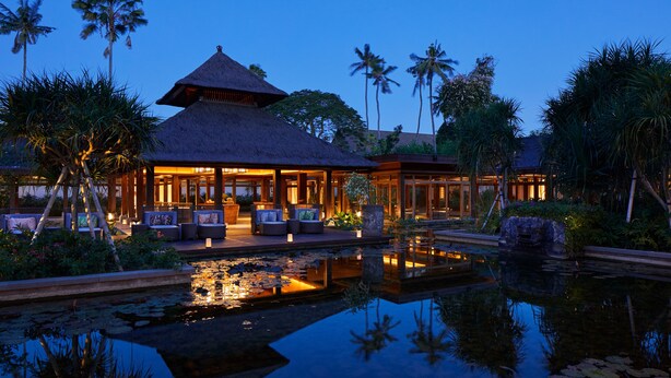 A resort with a thatched-roof building, a pool with lily pads, and tropical vegetation. - ANDAZ BALI, BY HYATT (Denpasar)
