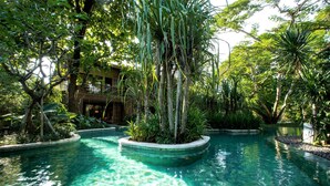 A pool surrounded by lush greenery and a building with a balcony. - ANDAZ BALI, BY HYATT (Denpasar)