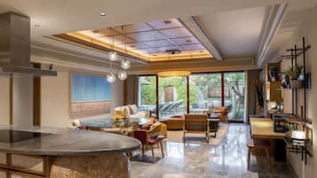 A spacious living area with a central round table, comfortable seating, and a view of the outdoors.