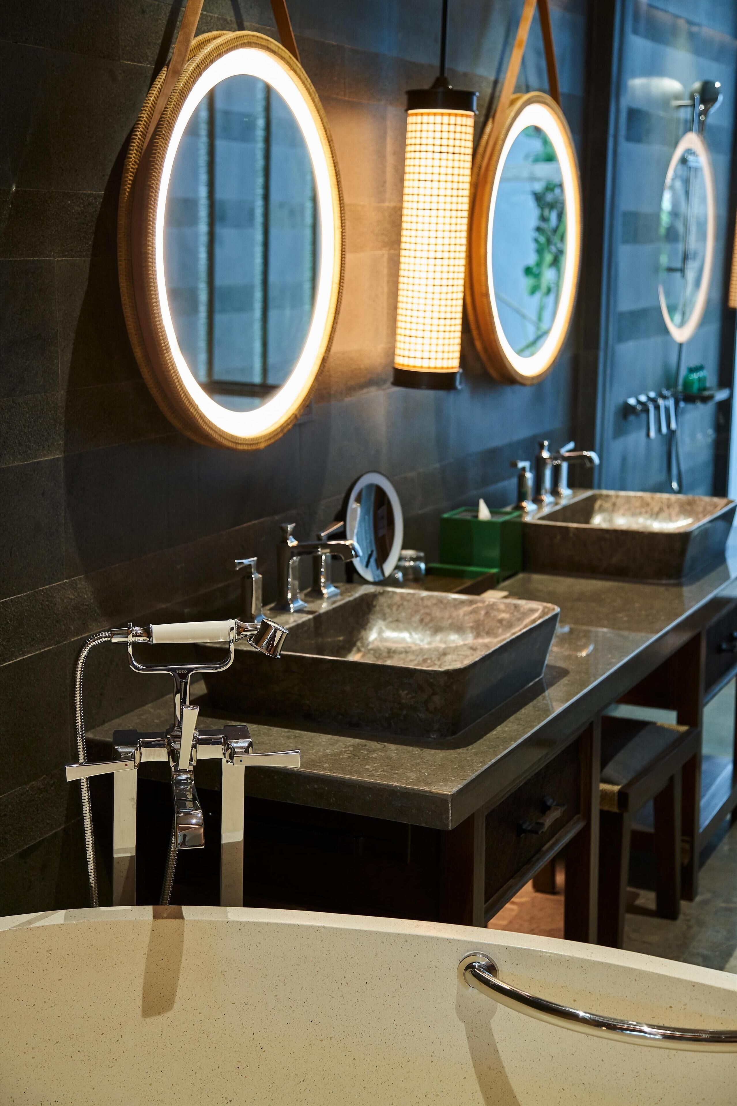 Un baño moderno con dos lavamanos, un espejo grande e iluminación colgante.