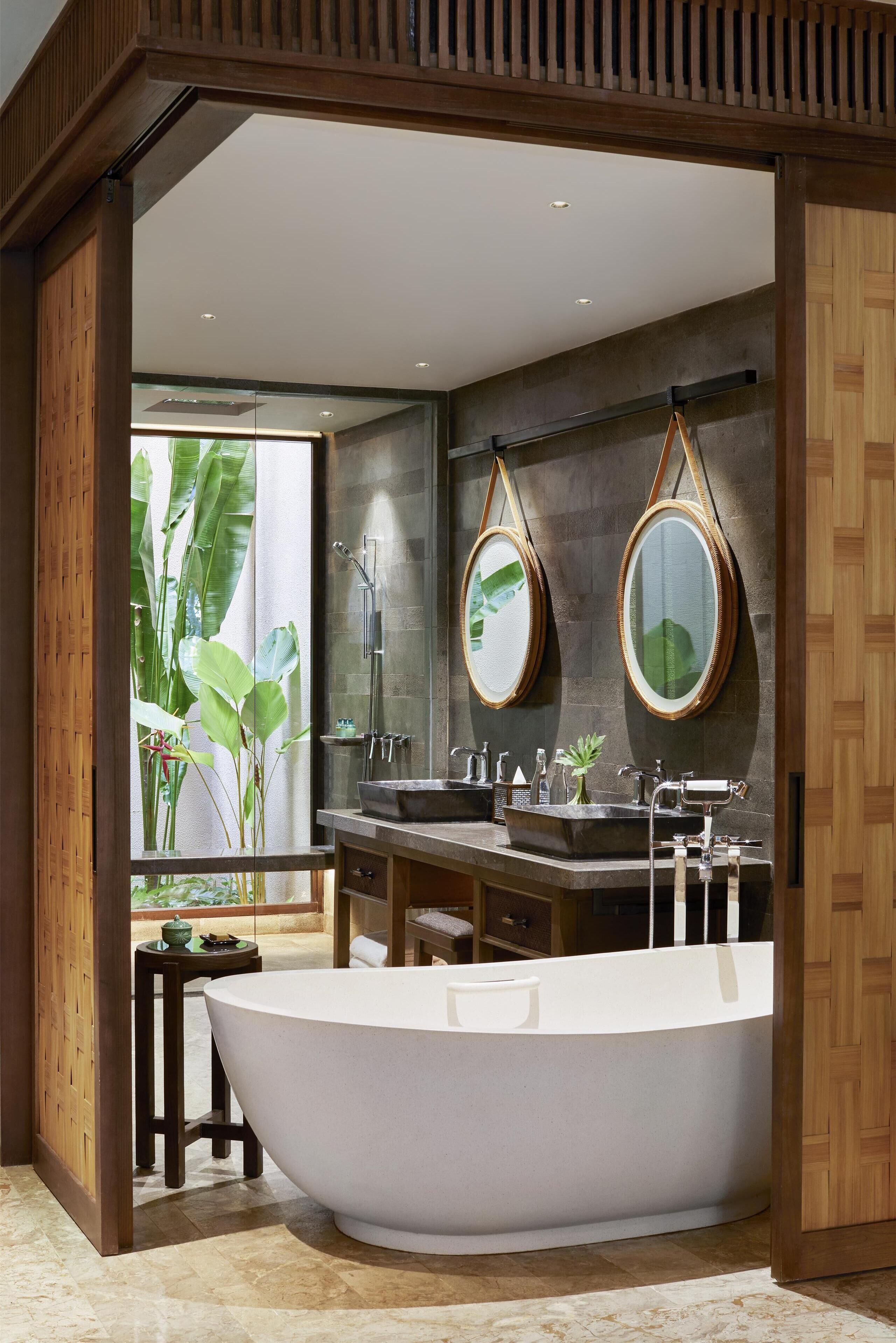 A modern bathroom with a freestanding bathtub, dual sinks, and large mirrors.