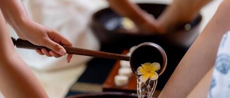 Fußbad mit Blumen und einer Person, die einen Wasserschöpfer hält.