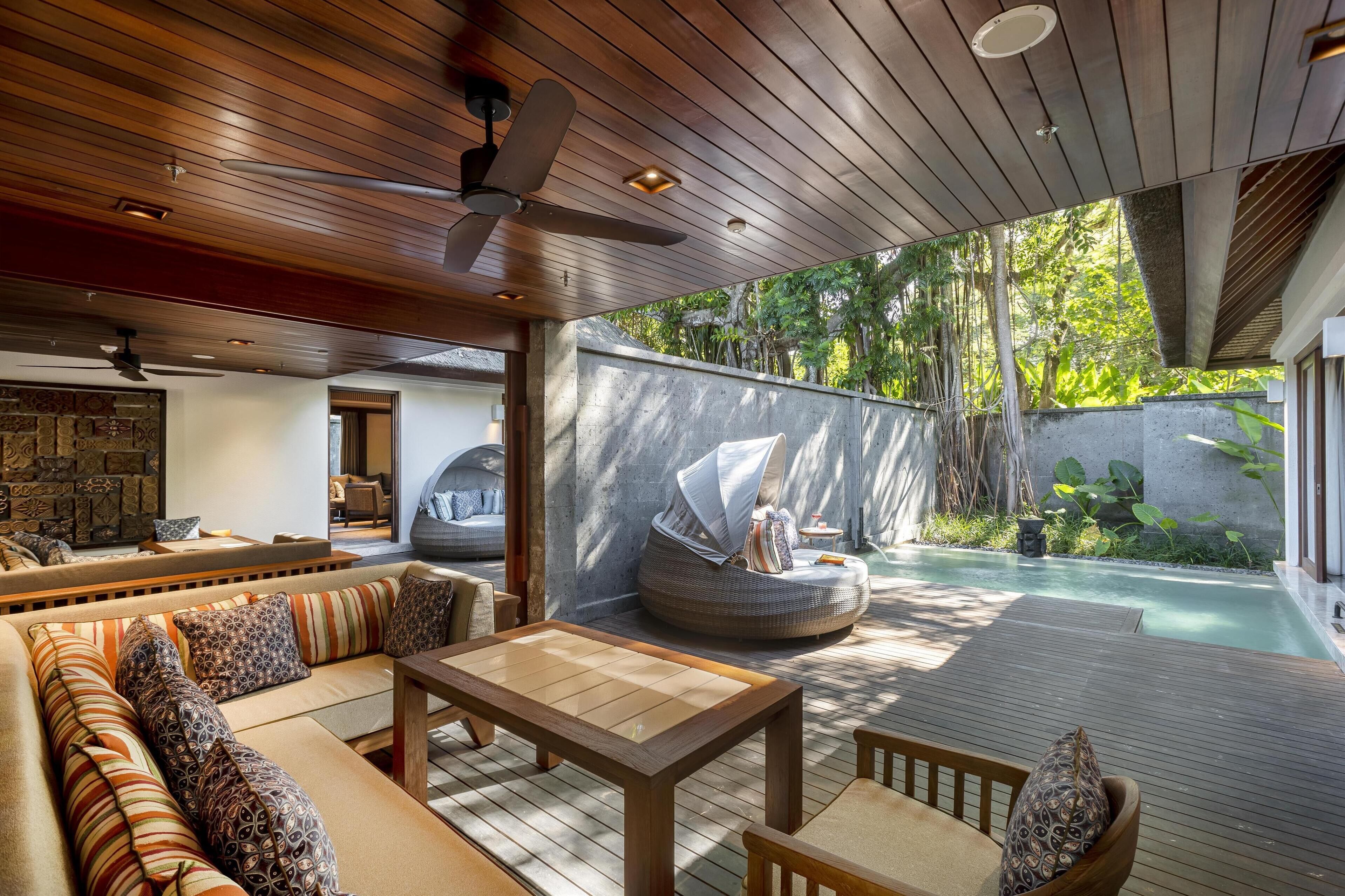 Un espace de vie extérieur moderne doté d’une terrasse en bois, d’une piscine et d’un coin salon avec un canapé et une table.