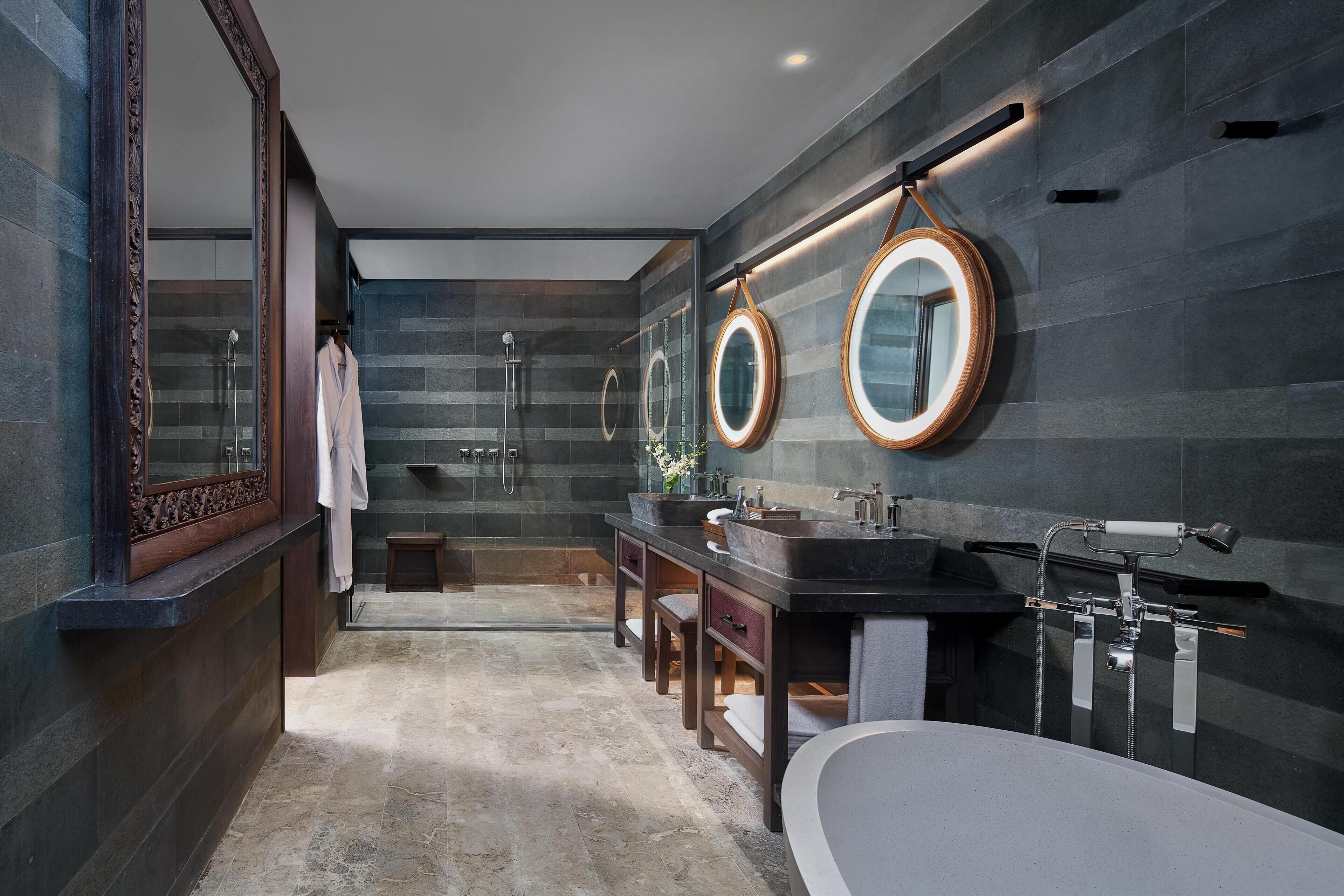 Un baño moderno con un espejo grande, dos lavamanos, una bañera y una ducha.