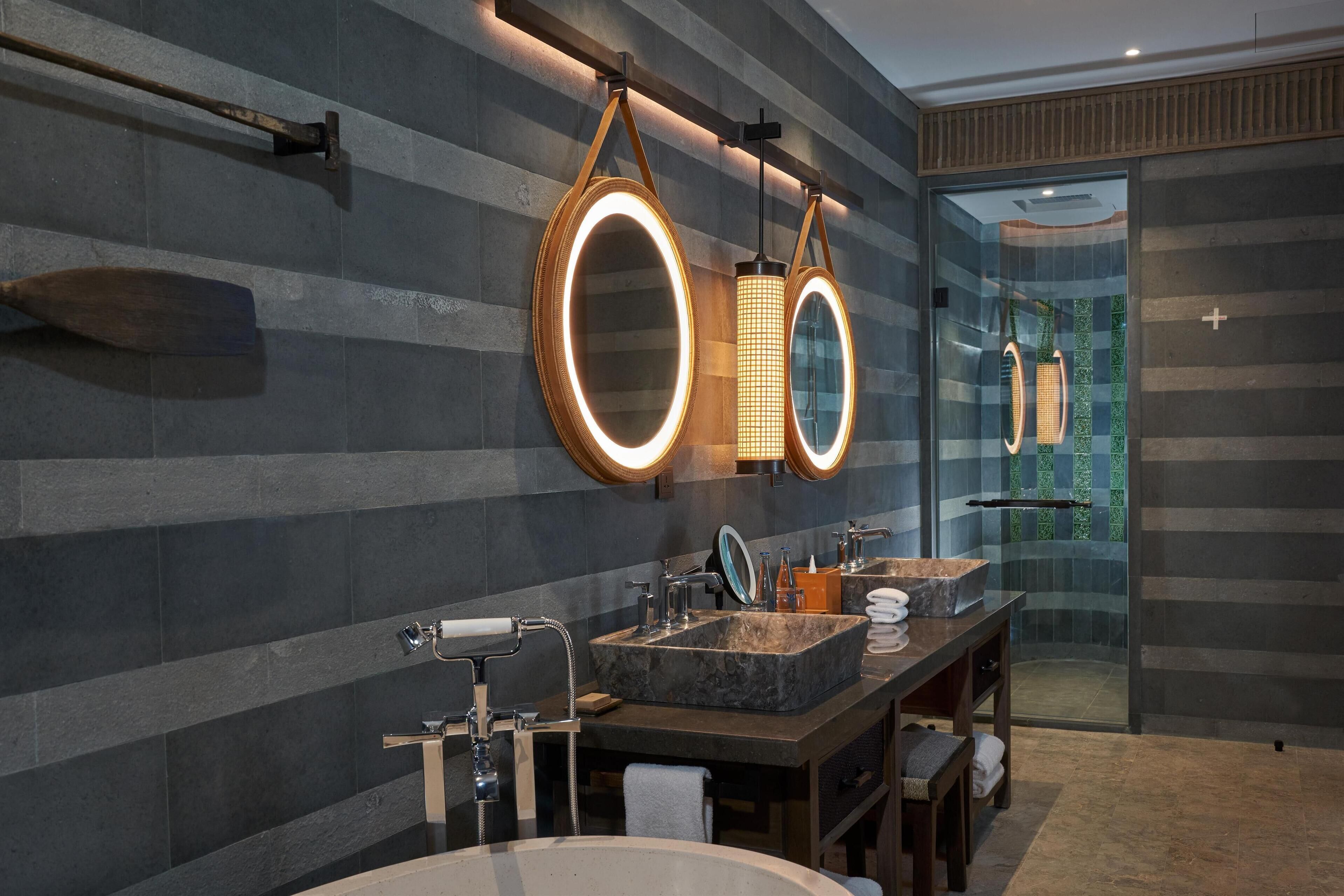 Un baño moderno con un espejo grande, dos lavamanos y una cabina de ducha de vidrio.