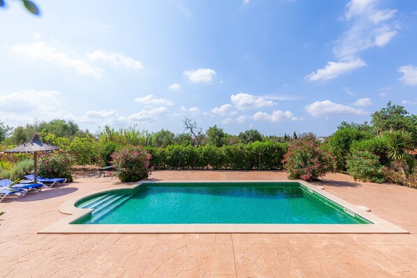 A rectangular swimming pool with a tiled deck, surrounded by greenery and a clear sky. - Casa Acuario-Géminis in Mallorca (llucmajor)