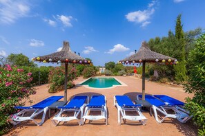 A poolside area with lounge chairs and thatched umbrellas. - Casa Acuario-Géminis in Mallorca (llucmajor)