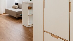 A minimalist room with a bed, a white wardrobe, and a small table with a plant. - Modern "Hus Apartment - Nr. 4" with Balcony, Garden & Wi-Fi (Olang)