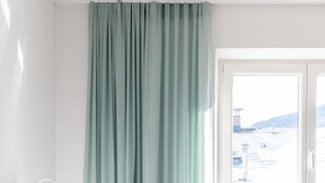 A hotel room with two beds, a window with a view of a snowy landscape, and a green curtain. - Modern "Hus Apartment - Nr. 4" with Balcony, Garden & Wi-Fi (Olang)