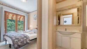 A bedroom with a bed, a window with curtains, a bathroom with a sink and mirror. - Beautiful Apartment “Residence Tatiana A3” with Pool, Terrace (Tremosine)