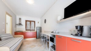 A compact kitchen with a bed, a dining area, and a TV mounted on the wall. - Beautiful Apartment “Residence Tatiana A3” with Pool, Terrace (Tremosine)