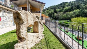 A stone structure with an arched opening, a balcony with a railing, and a view of a green landscape with trees and a hill in the background. - Beautiful Apartment “Residence Tatiana A3” with Pool, Terrace (Tremosine)