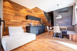 Ein modernes Interieur mit einer Holzverkleidung, einer Couch, einem Esstisch und einer Küchenzeile.