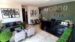 A modern hotel lobby with a reception desk, seating area, and artwork on the walls.