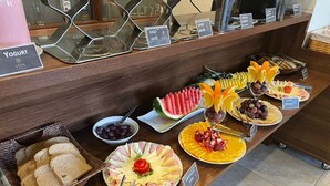 A buffet with various food items including yogurt, juice, water, cheese, ham, and bread.