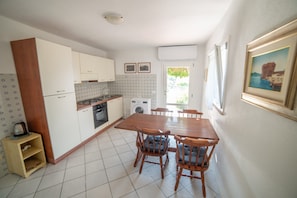 Une cuisine de taille réduite comprenant une table à manger, des chaises et un lave-linge.