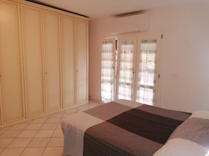 Une chambre à coucher avec un lit, une armoire et une porte-fenêtre coulissante.