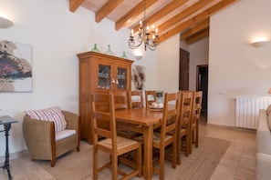 A dining area with a wooden table and chairs, a cabinet with glass doors, a chandelier, and a painting on the wall.