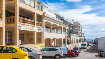 Un edificio de varios pisos con balcones, un letrero de centro de buceo y coches estacionados.