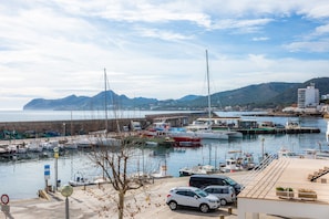 Un port de plaisance avec des bateaux amarrés, un pont et une chaîne de montagnes en arrière-plan.