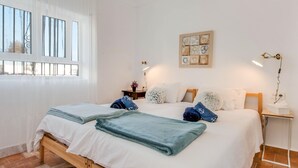 Hotelkamer met een bed, nachtkastje, kunstwerk aan de muur en raam met gordijnen.