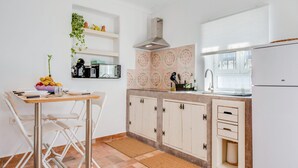 Een keuken met witte kasten, een roestvrijstalen afzuigkap, een spoelbak en een raam.
