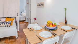 Een eetruimte met een houten tafel, witte stoelen en een schaal fruit.