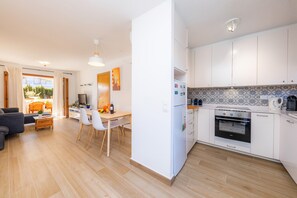 Eine moderne Küche mit weißen Schränken, einem eingebauten Backofen und einem Essbereich mit Tisch und Stühlen.