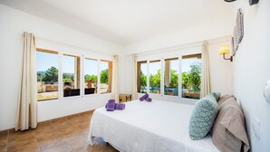 Une chambre à coucher avec un lit, des fenêtres, des rideaux et une vue sur la verdure.