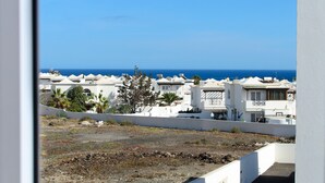 Une zone résidentielle côtière avec des bâtiments blancs, un ciel bleu dégagé et la mer en arrière-plan.