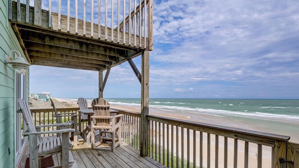 A wooden deck with two Adirondack chairs and a table, overlooking a beach with waves. - Direct Oceanfront with 4 Bedrooms, amazing ocean views and beach access- Adjoining side available... (North Topsail Beach)