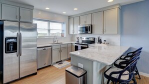 A modern kitchen with stainless steel appliances, a marble countertop, and a built-in island with bar stools. - Direct Oceanfront with 4 Bedrooms, amazing ocean views and beach access- Adjoining side available... (North Topsail Beach)