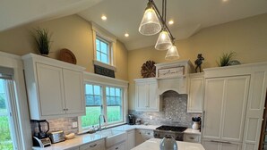 A modern kitchen with white cabinetry, a large island, and pendant lighting. - Breathtaking views of the Ocean, Incredible Sunrise, Sunsets and Jenness Beach (Rye)